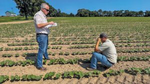 White man standing in a field across from a white man kneeling