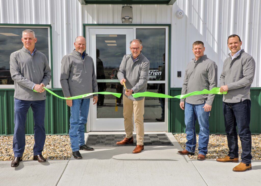 Group of five men standing in front of a building for a ribbon-cutting ceremony.