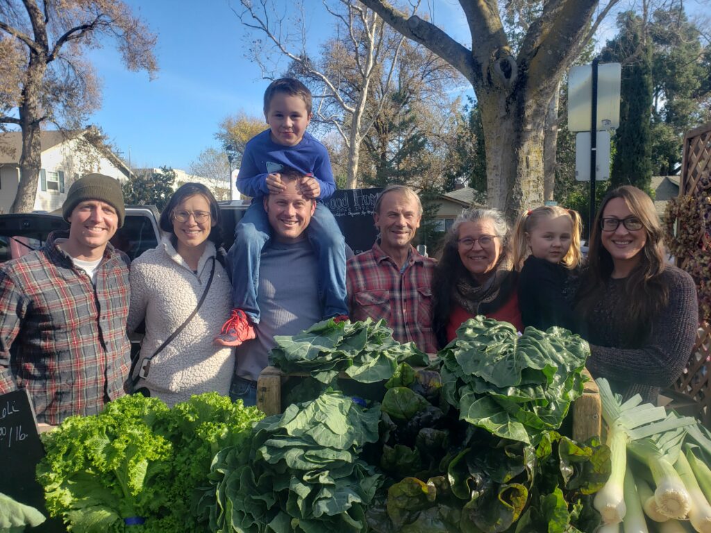 Good Humus Produce’s family members in front of leafy greens.