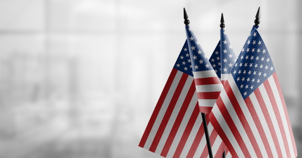 Small flags of the USA on an abstract blurry background.