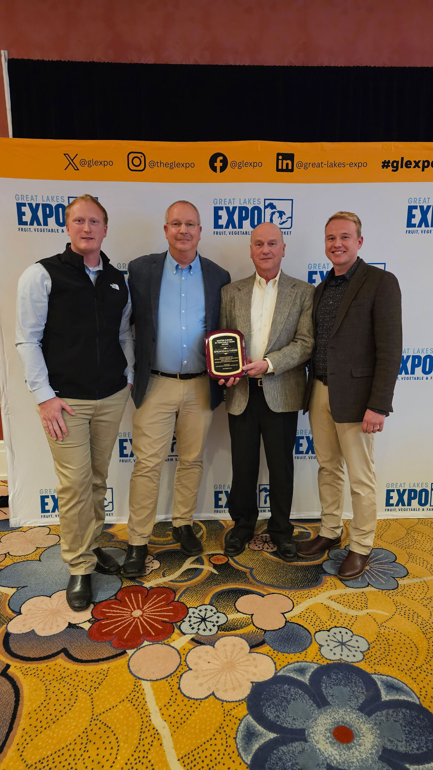 Four men from Springdale Farms standing in front of a Great Lakes EXPO banner