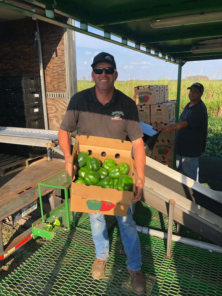 Jessie Bedner holding a carton of green bell peppers.