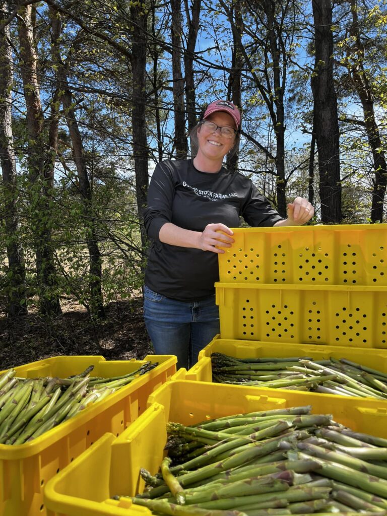 photo of Mary Sheppard of Golden Stock Farms in field with crates of asparagus