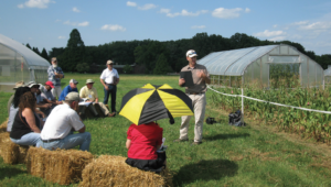 Matt Kleinhenz speaking to a group of people perched on hay bales