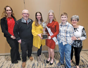 Six people standing together, with the two women in the middle holding a trophy