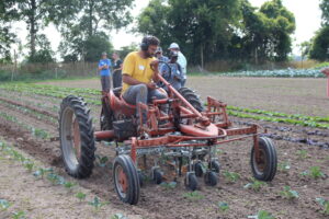 photo of man in field demonstrating equipment on tractor