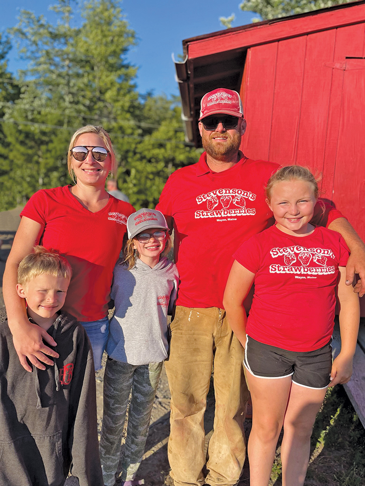 A family of five, from left to right: little boy, woman in red, little girl, man in red, little girl