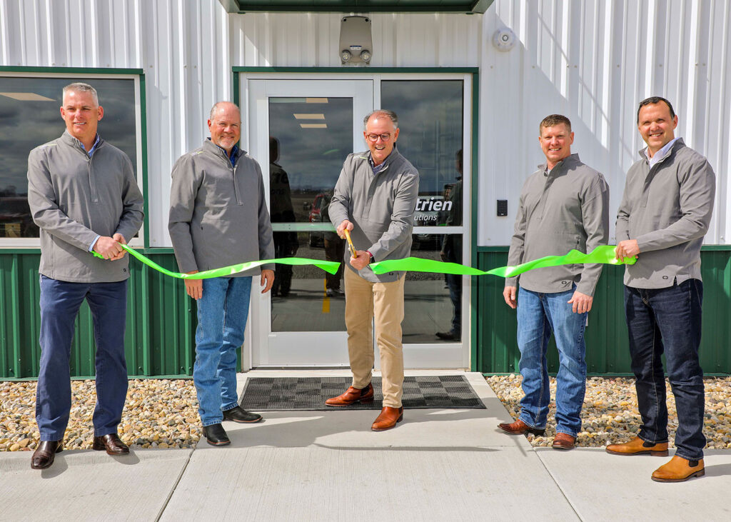 Group of five men standing in front of a building for a ribbon-cutting ceremony.