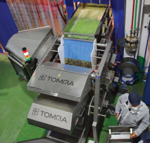 A giant machine with TOMRA stamped on the front sorting through vegetables